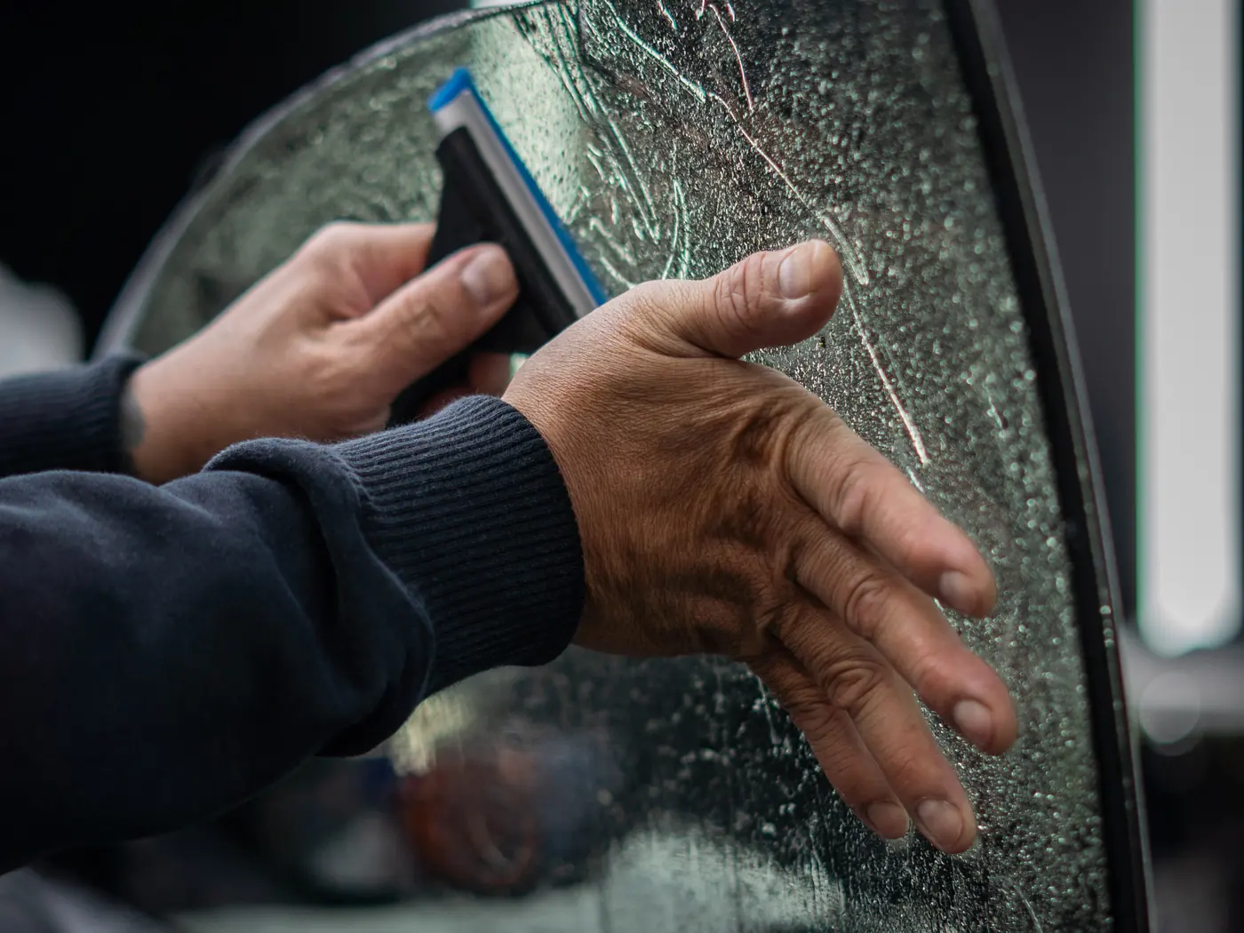 Technician squeegeeing tint film onto a car window